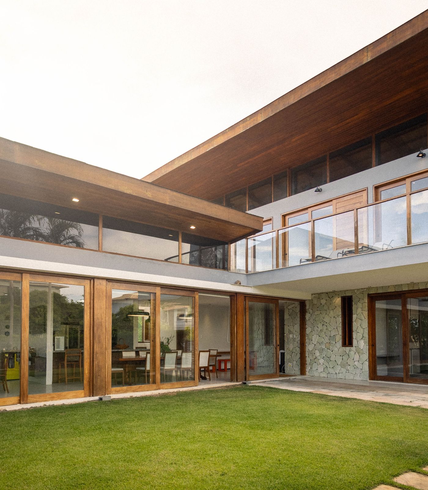 A contemporary home with floor-to-ceiling glass windows and sliding glass doors opening onto a courtyard.