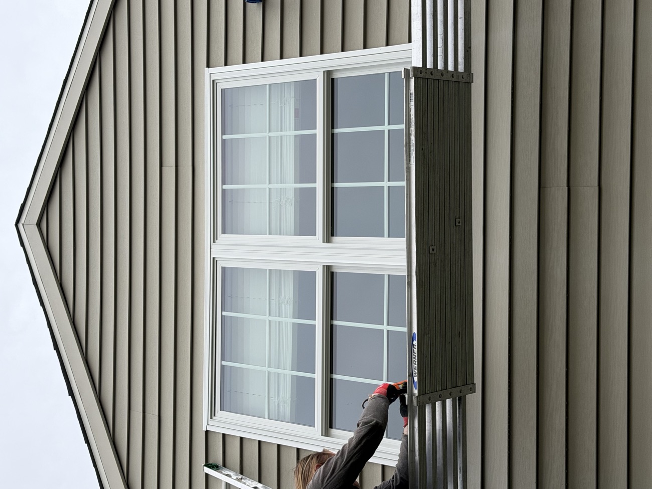 View from below of the new double window during installation, crew on a plank.