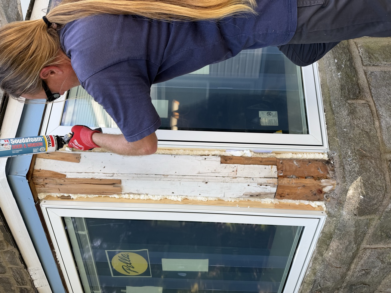 Installer sealing the new window against the stone façade.