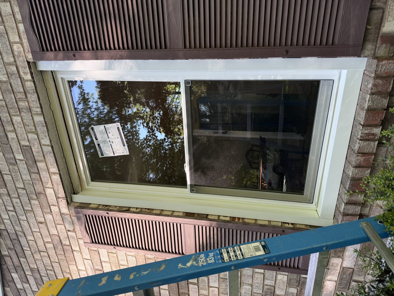Close-up of a finished double-hung window with the manufacturer label still on the glass.